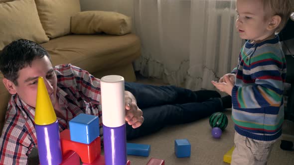 Happy Father Building Toy Castle. Child Ruining And Throwing Toy Bricks In Room