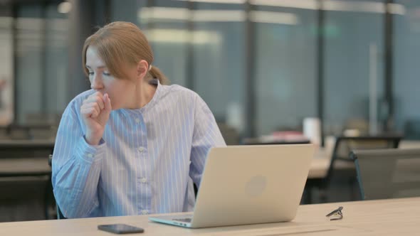 Young Woman Coughing While Using Laptop in Office