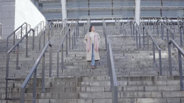 Portrait of Young Caucasian Businesswoman Walking Down the Stairs When Having Sharp Pain in Stomach