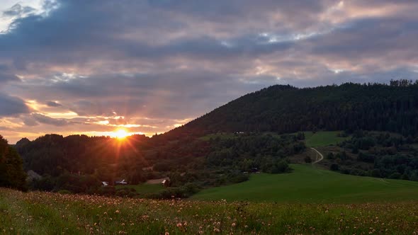 Sunset over the hills on a green meadow