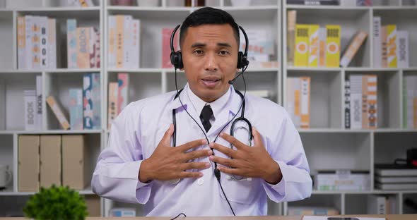 Doctor with headset making conference call and looking at camera