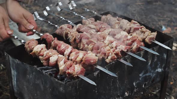 Female Hand Grilling Raw Meat on Grill. Cooking Meat Barbecue on Charcoal Grill