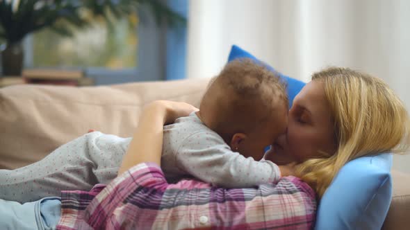 Smiling Caucasian Mother Holding Adopted Mixed-race Baby at Home