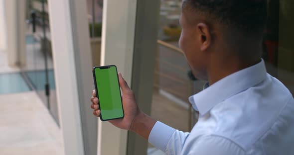 Overshoulder View of Afro American Man Holding Smartphone and Touching Green Screen While Making Yes