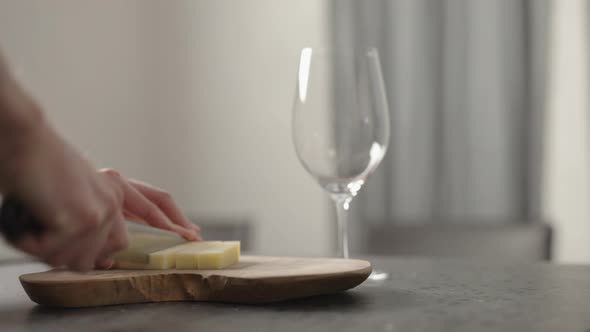 Man Cutting Vintage Cheese on Kitchen with Wineglass