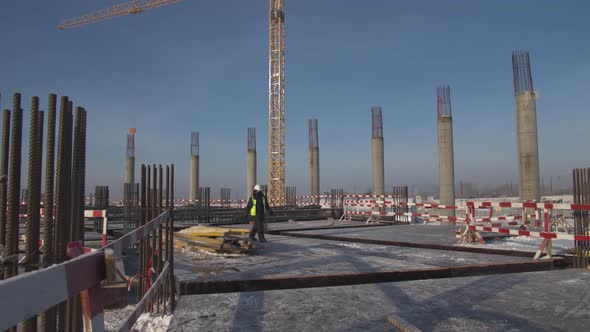 Employee Walks Along Construction Site on Winter Day