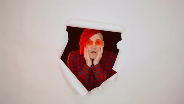 Young Man in Sunglasses with Shocked Facial Expression in Hole of White Background