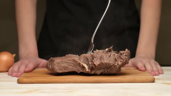 Woman sweeps fresh vegetables from the board and puts a piece of boiled meat