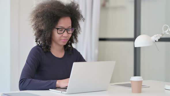 African Woman with Laptop Pointing at Camera