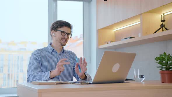 Man works remotely with colleagues at work through a laptop using video communication.