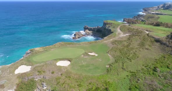 Scenic view of rocky seashore landscape, green golf course greens above edge of cliffs and sandy pit