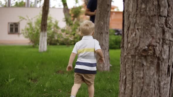 A Little Boy is Playing with His Father in Hide and Seek in the Garden