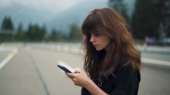 Gimbal Shot of Woman with the Phone on Background of Highway Road