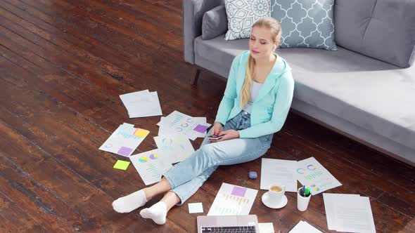 Young woman works with documents using a laptop at home.