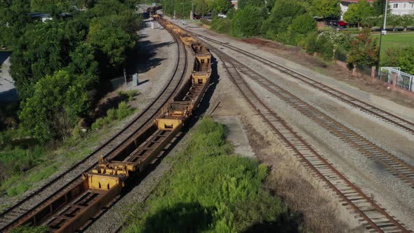 Aerial view of rusty train carsing through a curve on a set of tracks on a sunny day in the morning.