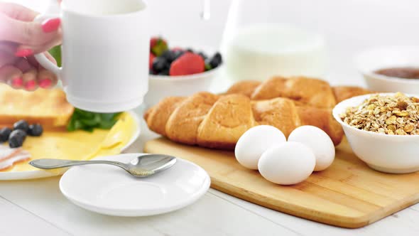 Closeup Female Hand Putting White Cup with Morning Coffee on Serving Table Side View