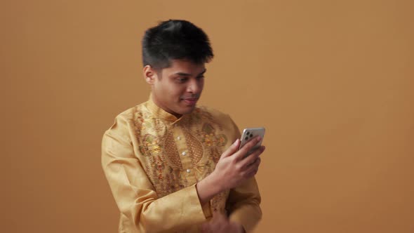 Cheerful Indian man in national cloth looking at phone