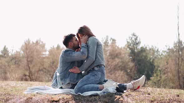 The Loving Couple of Man and Woman Are Kissing at Sunset in the Field