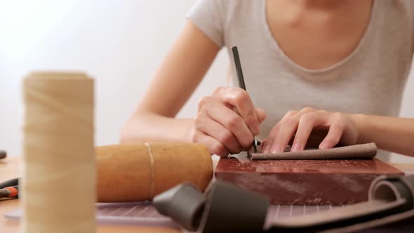 Woman making leather wallet