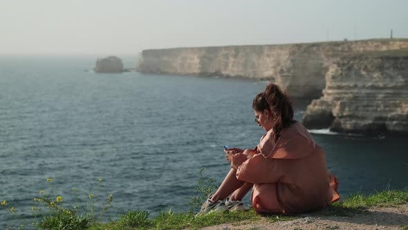 Woman Enjoying Solitudeness on Sea Shore Using Smartphone