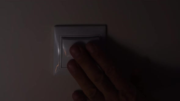 Hand Elderly Man Turns Off and On the Light From the Wall Switch