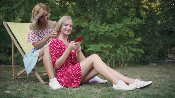 Two Friends Have a Good Time in the Park They Use a Smartphone