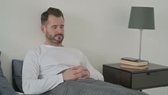 Man Taking Nap While Sitting in Bed