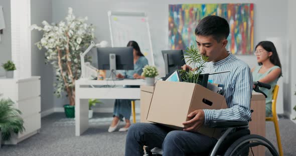 Disabled Man Dressed in Shirt Got Job in Company's Office He is Sitting in Wheelchair Holding Box