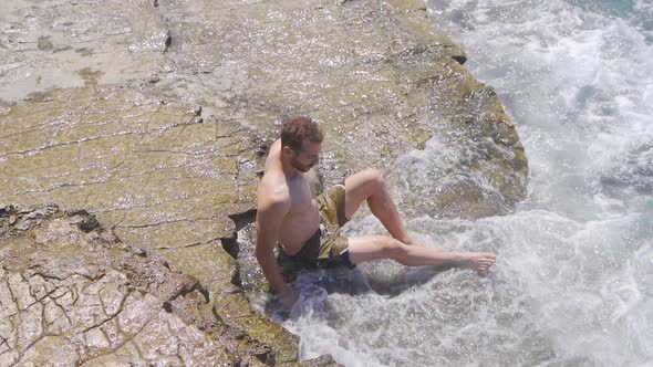 Young man sitting on the beach. Slow Motion.