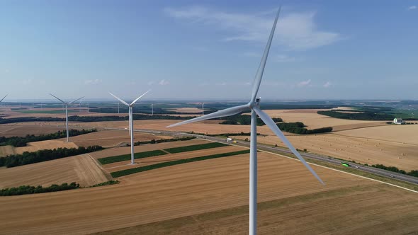 Large Wind Turbines with Blades in Field Aerial View Bright Orange Sunset Blue Sky Wind Park Slow