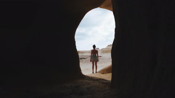 Back view of a young woman standing in front of a rocky mountain