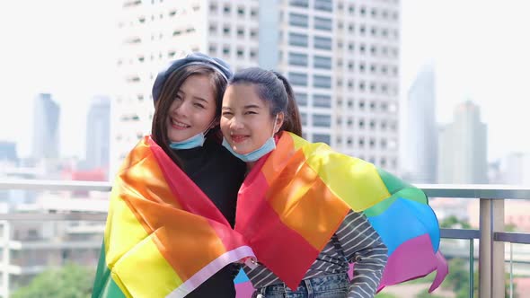 Happy loving homosexual lesbian LGBT couple with rainbow flag at city