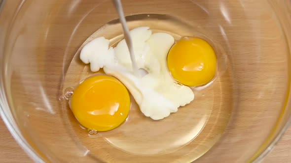 Milk Is Poured Into Plate with Eggs in Slow Motion