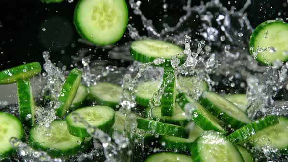 Super Slow Motion Shot of Cucumber Slices Falling Into Water on Black Background at 1000Fps