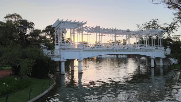 Aerial panning of white bridge over pond at Rosedal gardens in Palermo neighborhood at sunset, Bueno