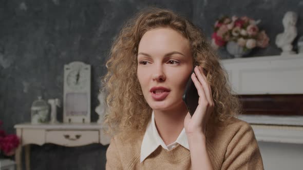 Close Up of a Young Caucasian Woman Shy Talking on a Phone Indoors