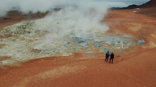 Two Tourists Looking at Steaming Fumaroles in Hverir Geothermal Area