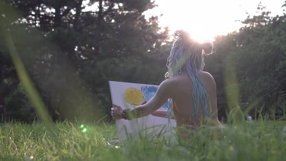 Young Woman Artist in Ethnic Clothes Paints a Picture Against the Backdrop of the Sunset