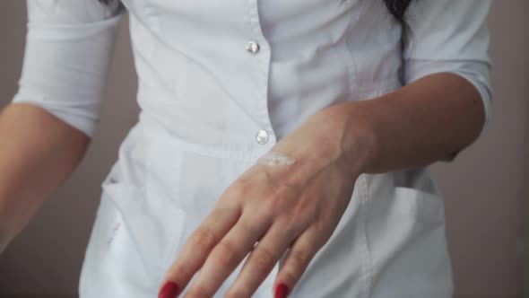 Close Up of Professional Beautician Shows How to Applying Body Lotion Cream on Hands