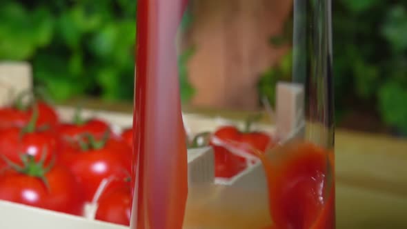 Closeup of Tomato Juice Poured in a Glass Jug Next to the Box Full of Tomatoes