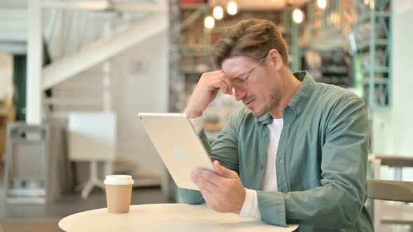 Disappointed Middle Aged Man Reacting To Loss on Tablet in Cafe 