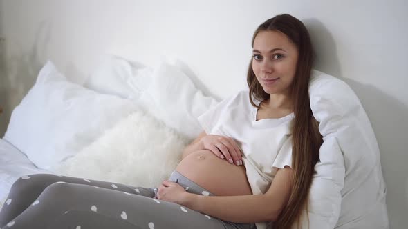 Young Woman Gently Touch Tummy and Look at Camera with Smile