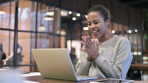 Excited African Woman Celebrating Success on Laptop