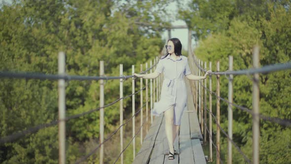 Woman in a Beautiful Dress, Walks on a Bridge in Woods