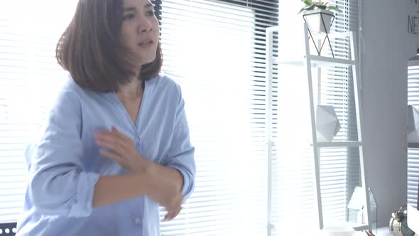 young strain asian woman working on laptop while sitting in a living room at home.