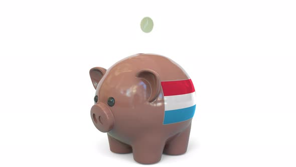 Putting Money Into Piggy Bank with Flag of Luxembourg