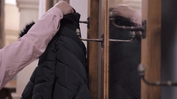 Woman gets her coat  hanging on vintage ornate  coat hanger hooks