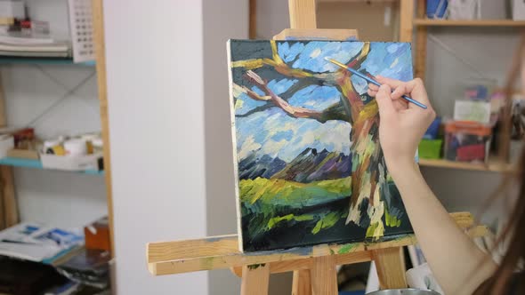 Woman Is Drawing By Wide Strokes of Paints on Canvas Depicting Landscape