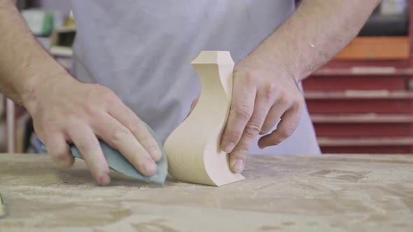 Artisan polishing wooden detail using sandpaper in carpentry workshop