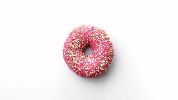 Top View Fresh Doughnut with Pink Glaze and Multicolored Sprinkle Turning Isolated on White